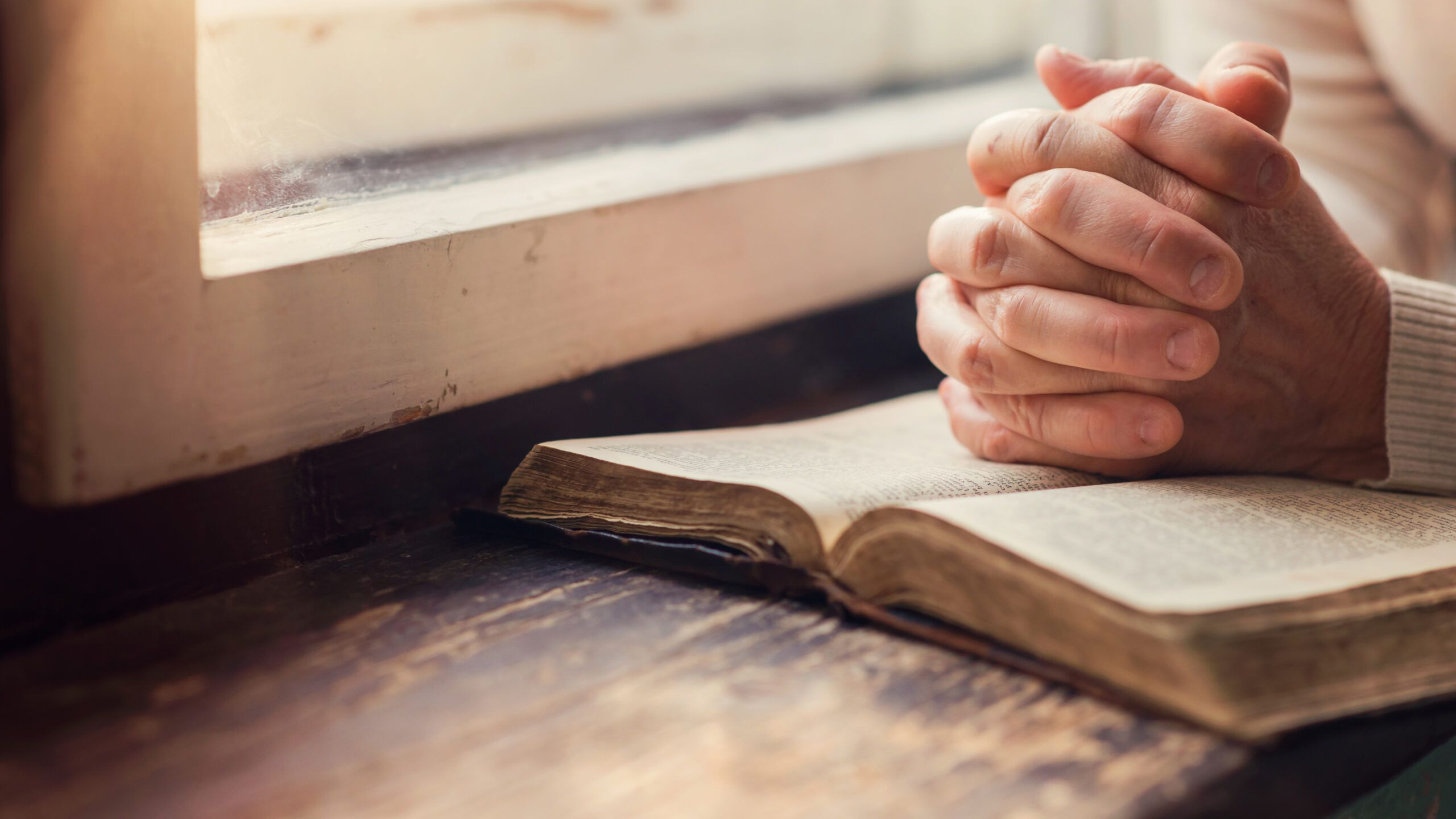 Hands clasped over a Bible