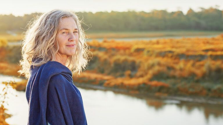 A contented, peaceful woman rests near a country stream