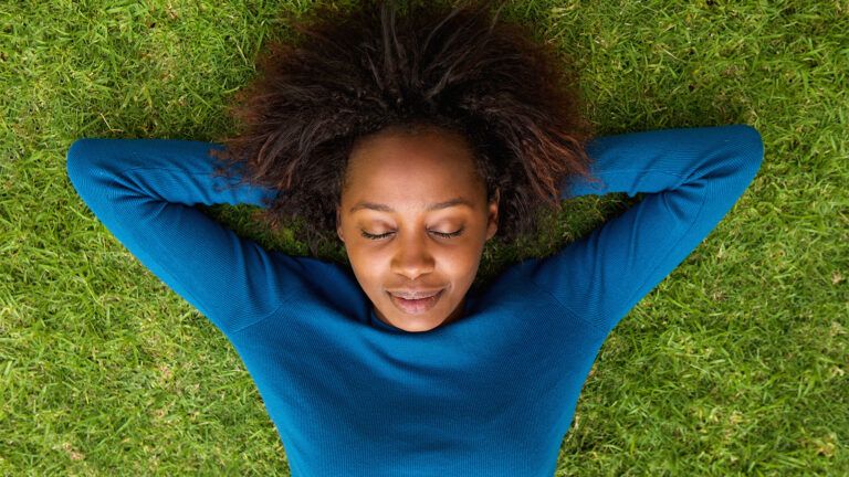 A woman rests on the green grass