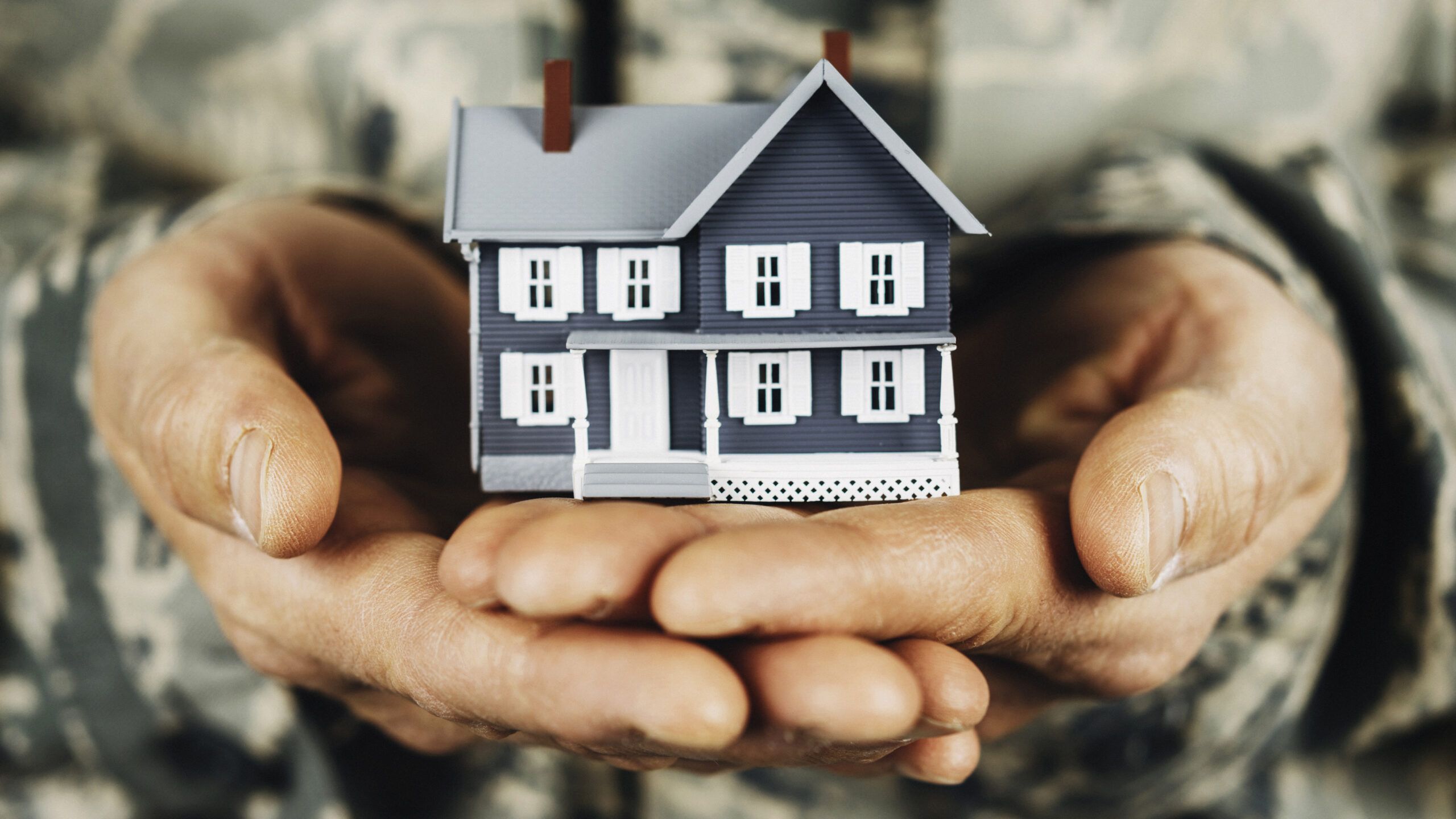 Military member holding miniature house