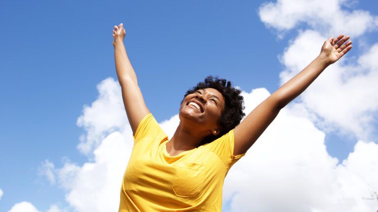 A joyful woman raises her arms in surrender