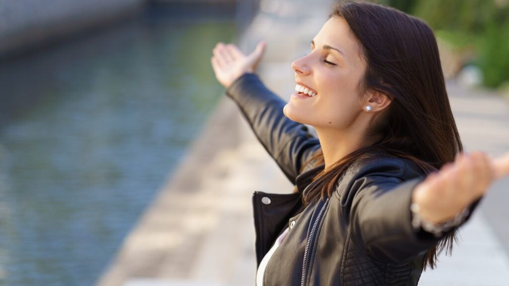 A woman stands with her arms outstretched showing her habit of gratitude