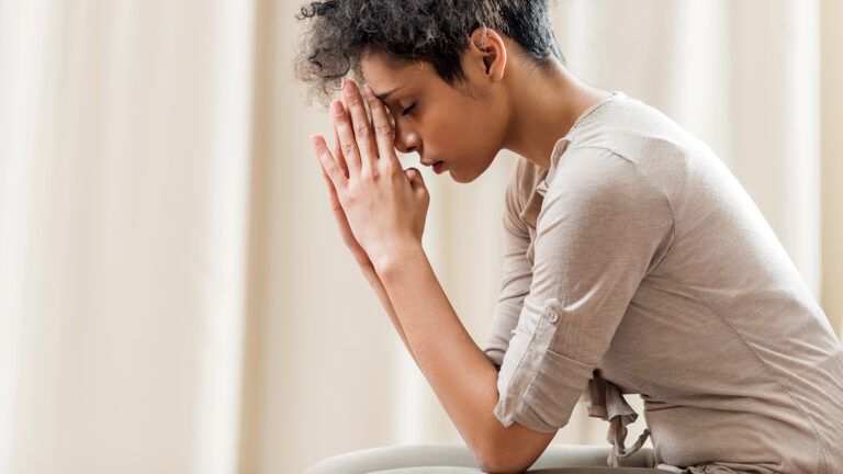 A woman clasps her hands in prayer