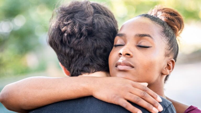 A young woman consoling her caregiver friend.