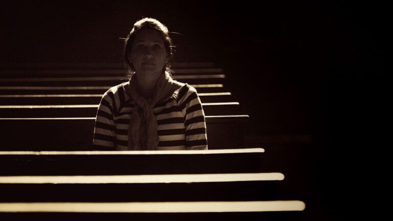 A woman prays alone in a darkened church