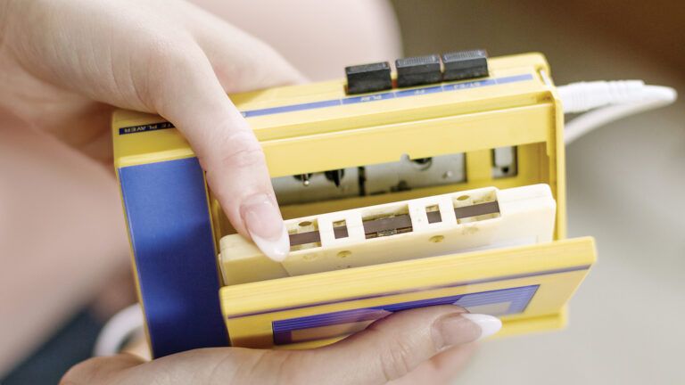 A woman loading a cassette tape into a cassette player.