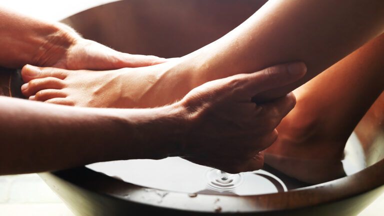 Hands wash feet in a basin