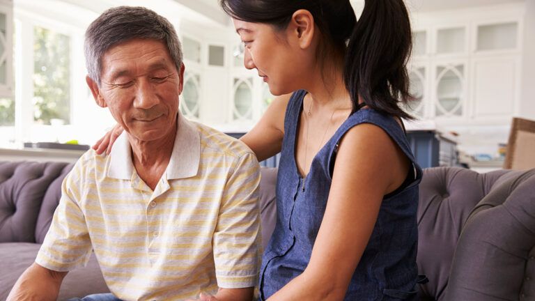 An adult daughter comforts her father who is dealing with dementia