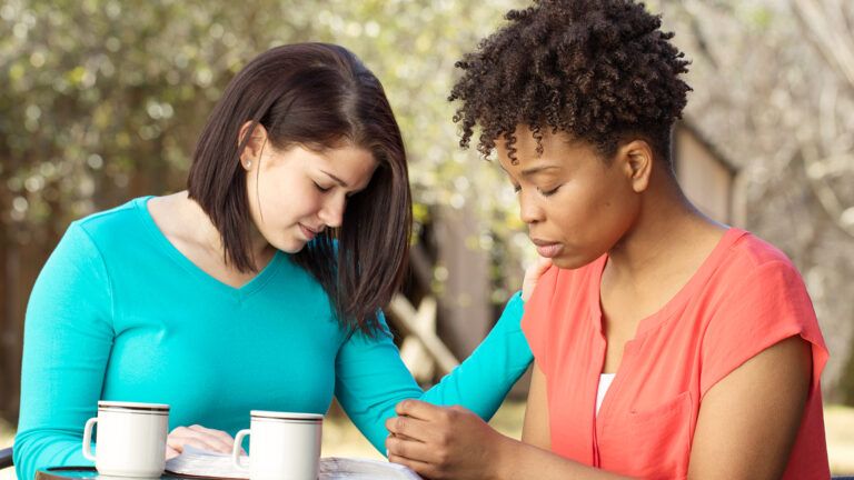 Two young women pray together