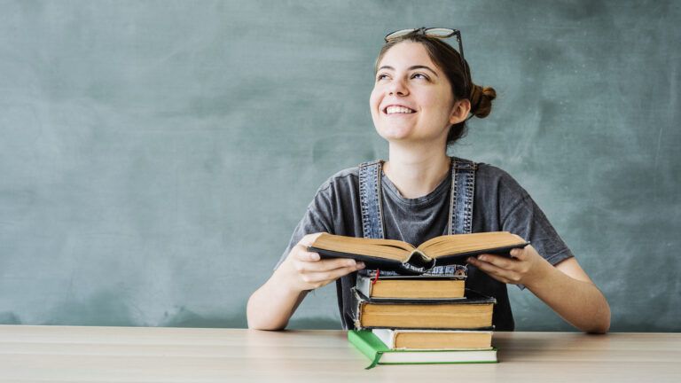 A smiling woman with a reading habits reads a book and looks up