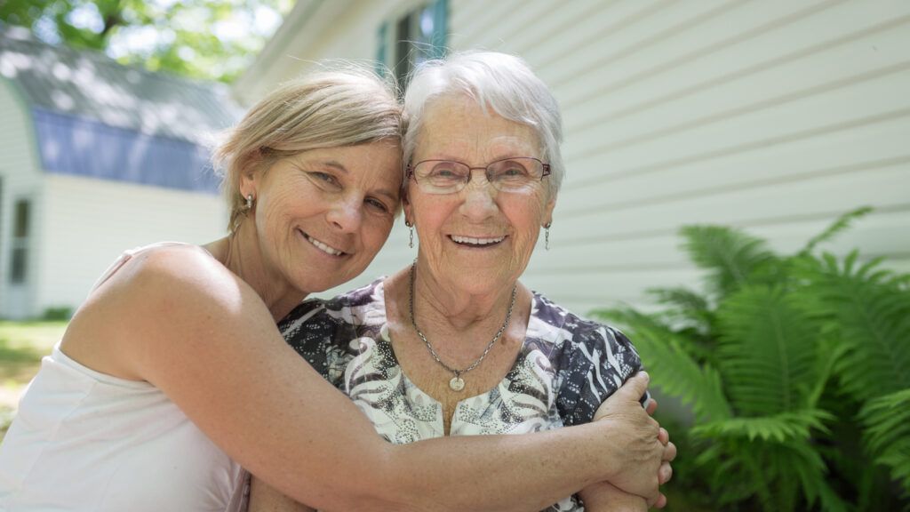 A woman in her golden years embracing her aging mother.