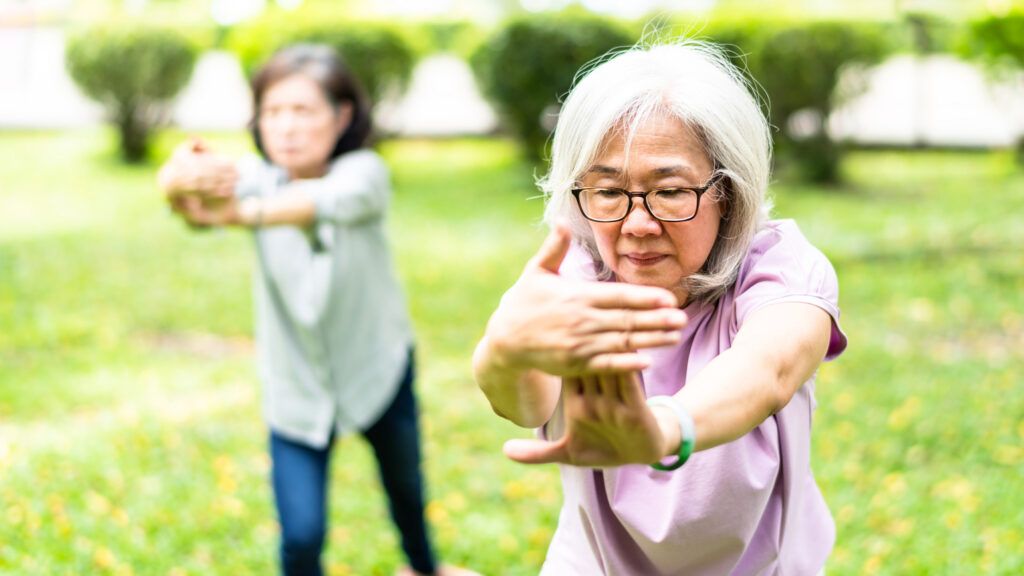 Two women practicing tai chi outdoors.