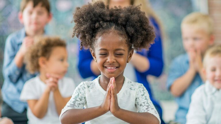 A young girl smiles as she prays