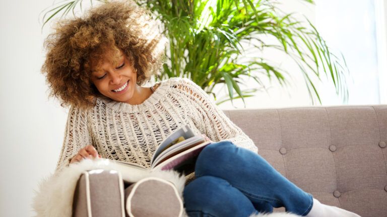 A woman on a sofa reading a book.