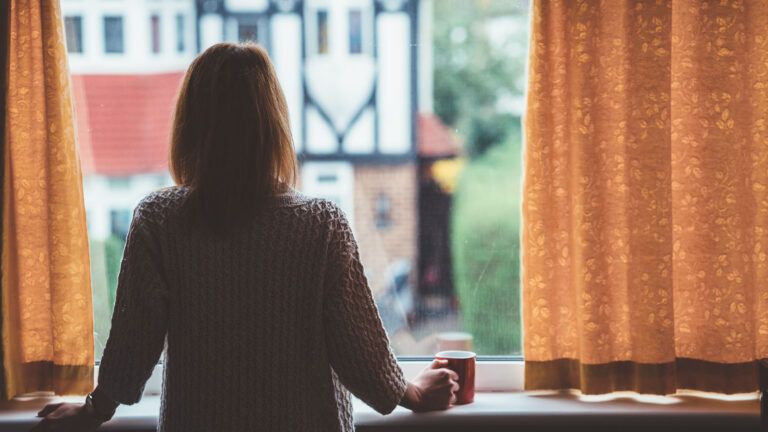 A woman having contemplative thoughts while looking out of her window.