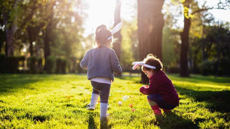 Two young girls participate in an Easter egg hunt.