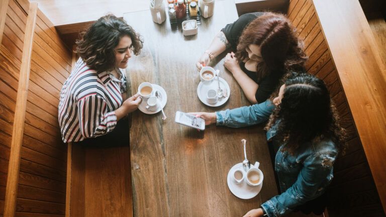 Three friends having coffee together in a cafe.