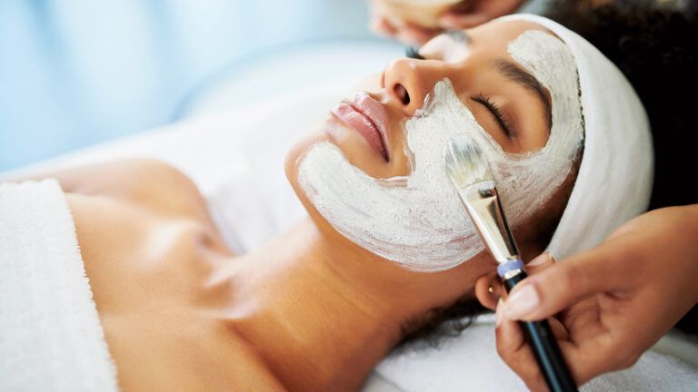 A young Afro-American woman receiving a spa facial treatment.