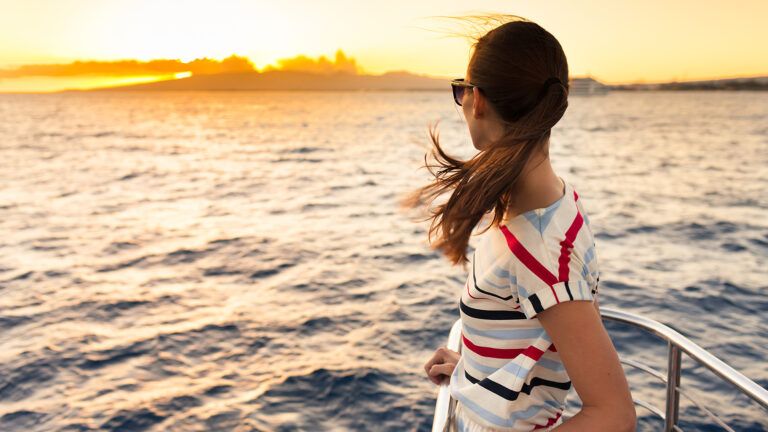 A woman rides a ferry at sunset