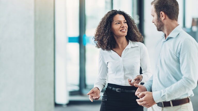 A woman at her workplace talking to a co-worker.