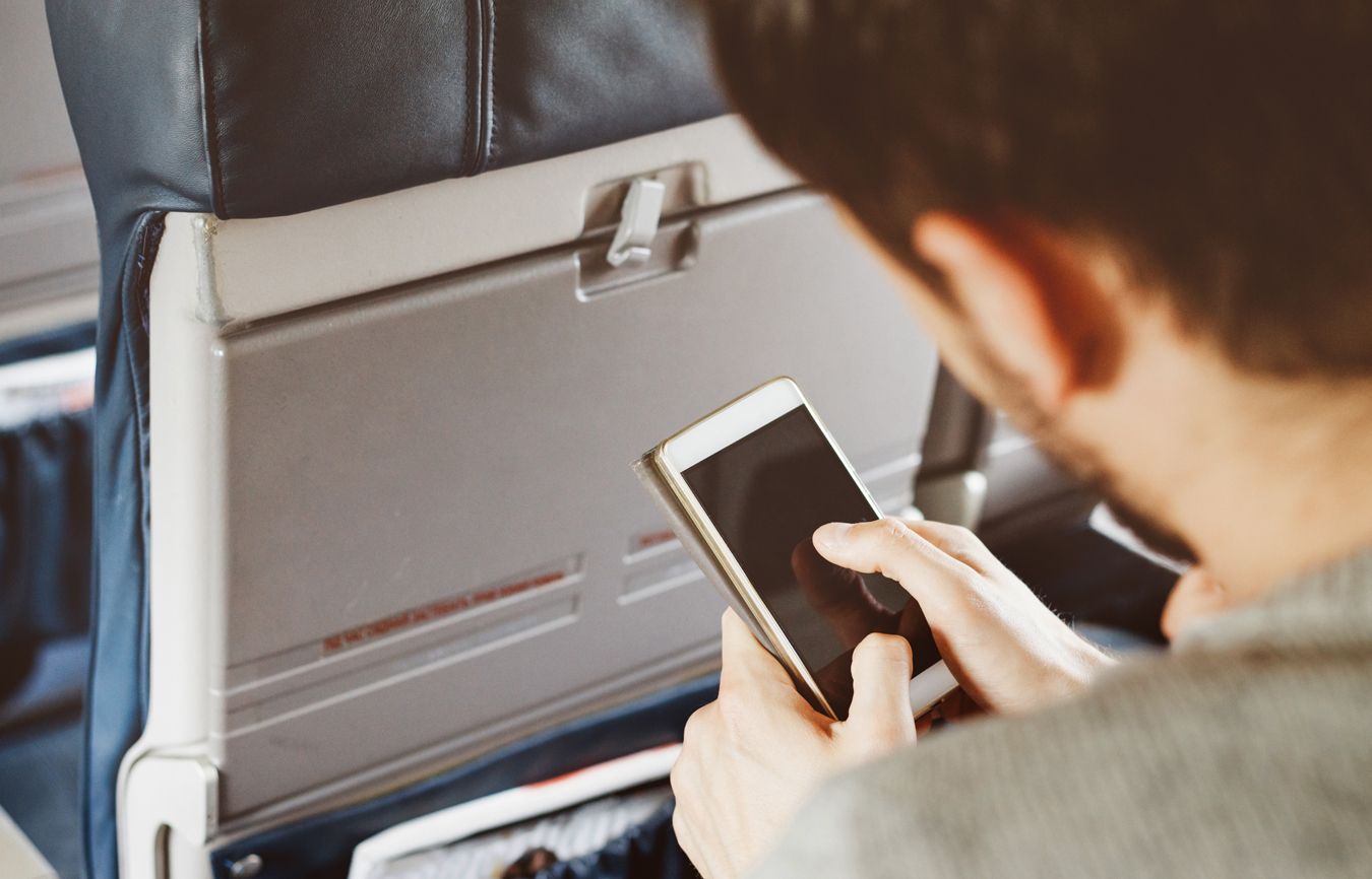 Man using his phone on a plane