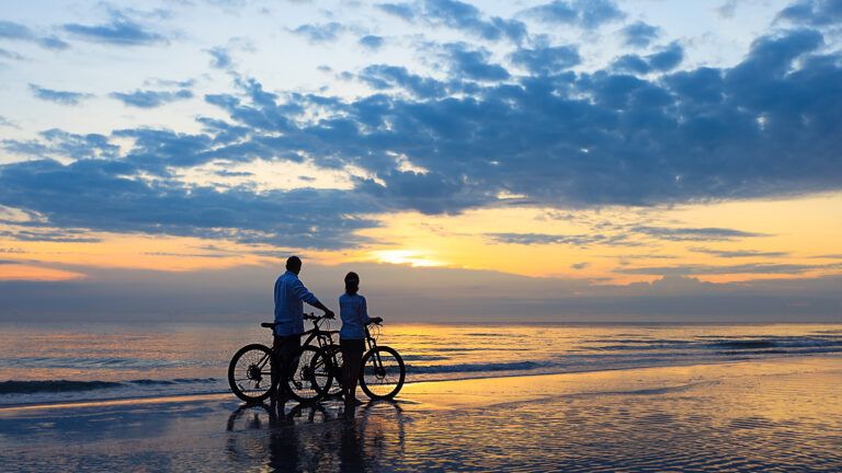 Couple riding their bikes on the beach