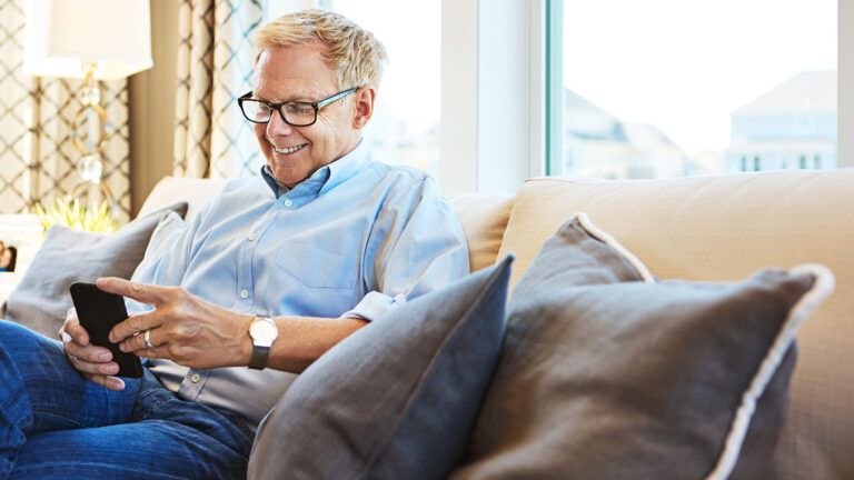 Man smiling while looking down at his phone