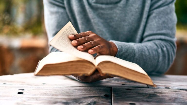 A man's hands hold an open Bible