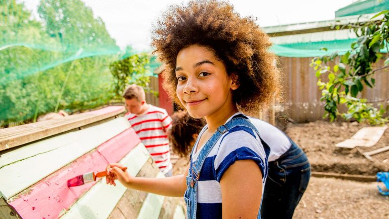 A young woman helps to paint a house