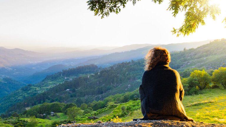 A woman finds calm by sitting on a hillside