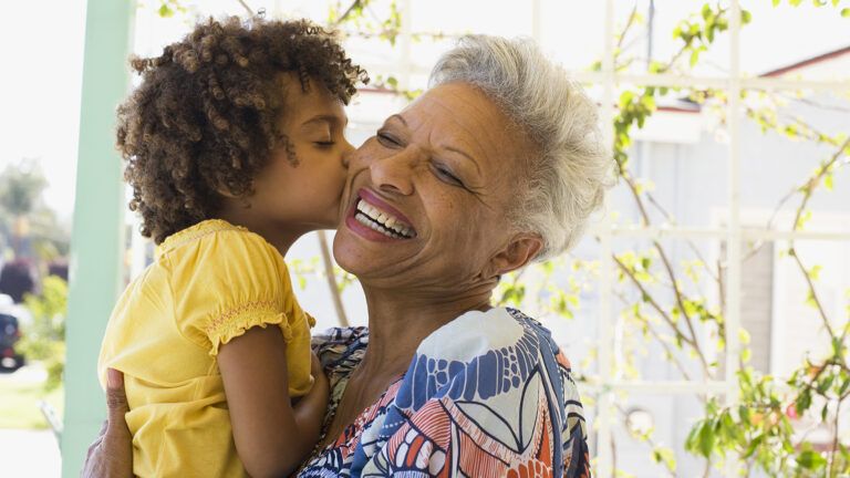 A grandmother receives a kiss from her granddaughter.