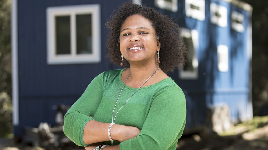 Sandy Blair stands in front of a Tiny House; photo by Dan MacMedan