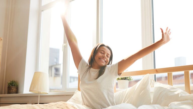 A woman waking up in bed during the morning.