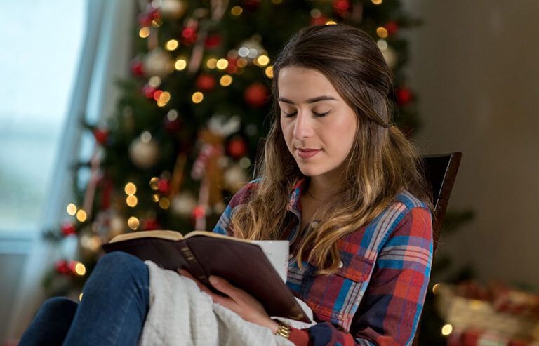 Young woman praying by the Christmas tree