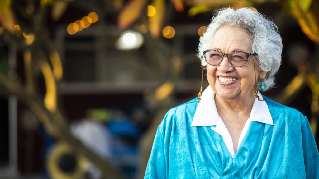 A woman in her golden years laughing outside; Getty Images