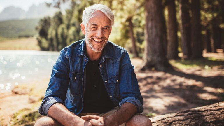 Happy man sitting near a lake