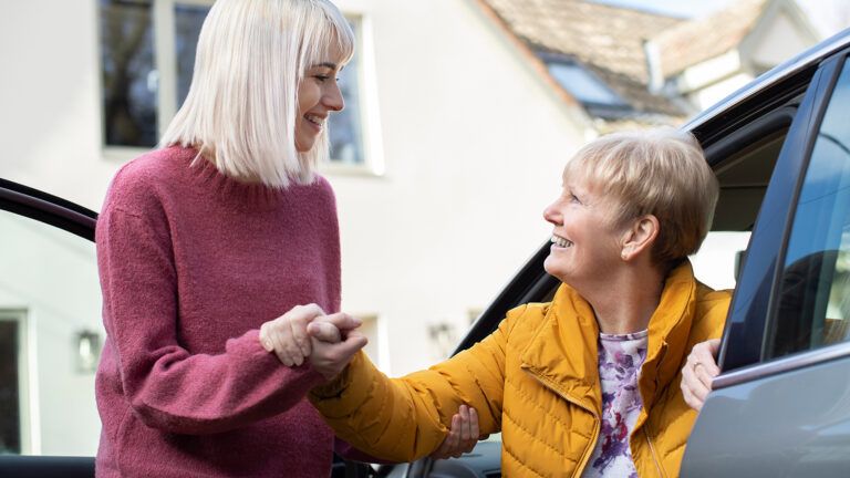 Woman helping older woman out of the car