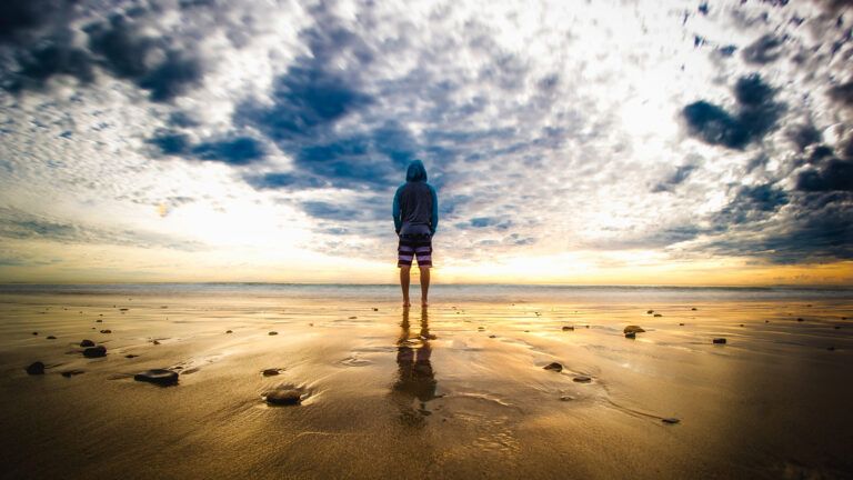 A young man greets th sunrise on a beach