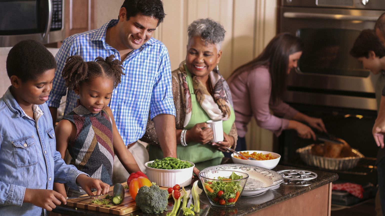 family in home kitchen cooking Thanksgiving dinner (Getty)