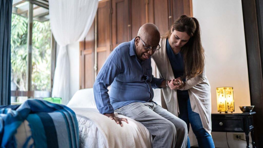 A caregiver helping an aging man; Getty Images