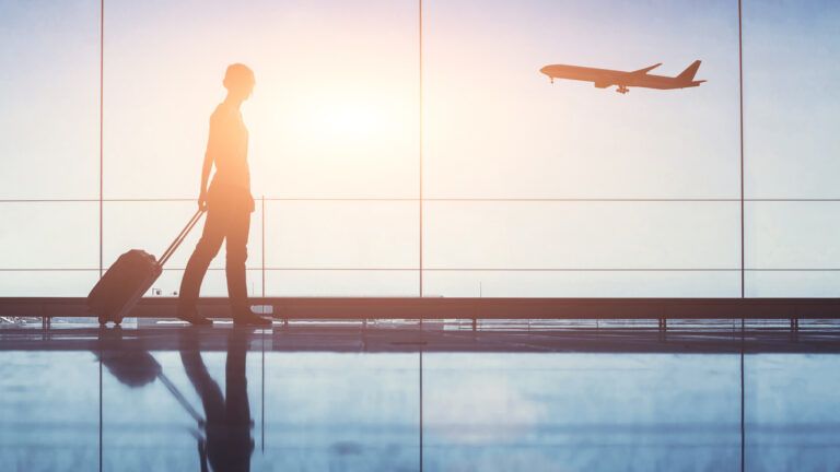 Woman walking through airport in sunlight (Getty Images)