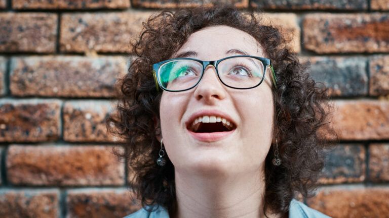 Woman looks up, gasping in amazement (Getty Images)