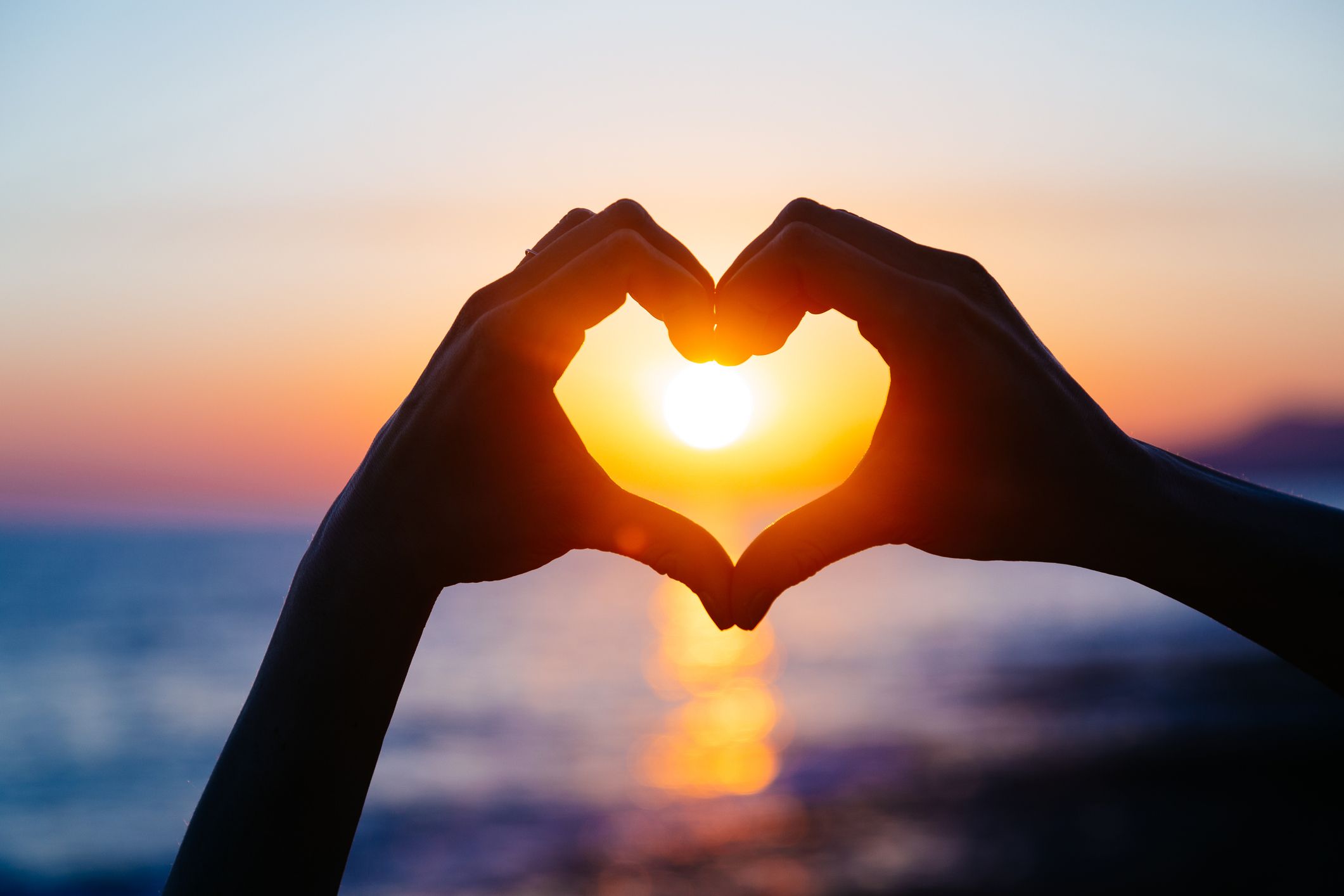 Hands making a heart at sunset for God's hands