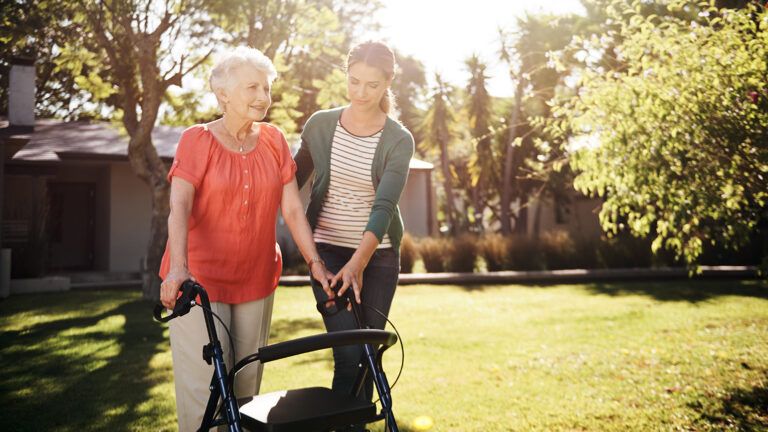 Adult daughter helping senior mother on a walker