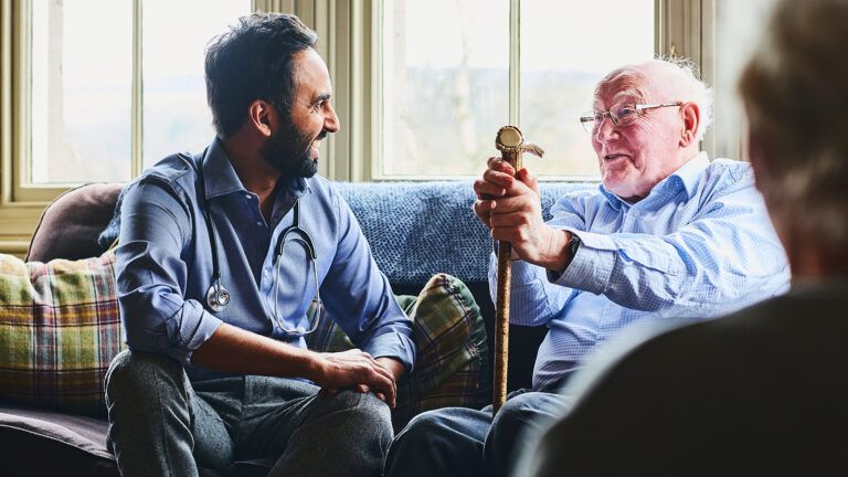 Young male caregiver talking to senior man