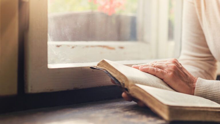 Woman reading a bible by a window