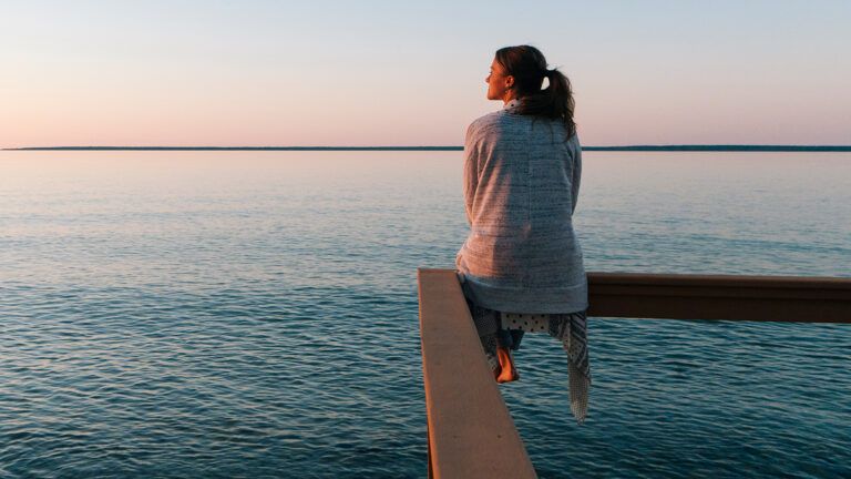 A woman gazes out from a lakefront pier