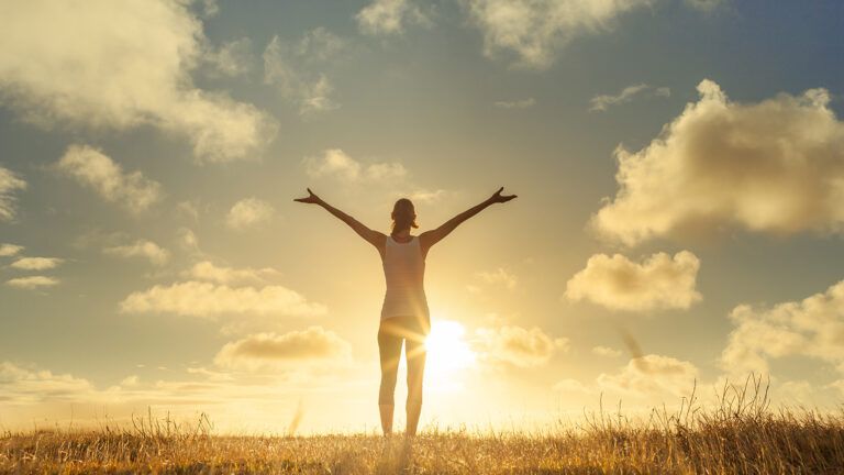 Woman stretching her arms out towards the sun