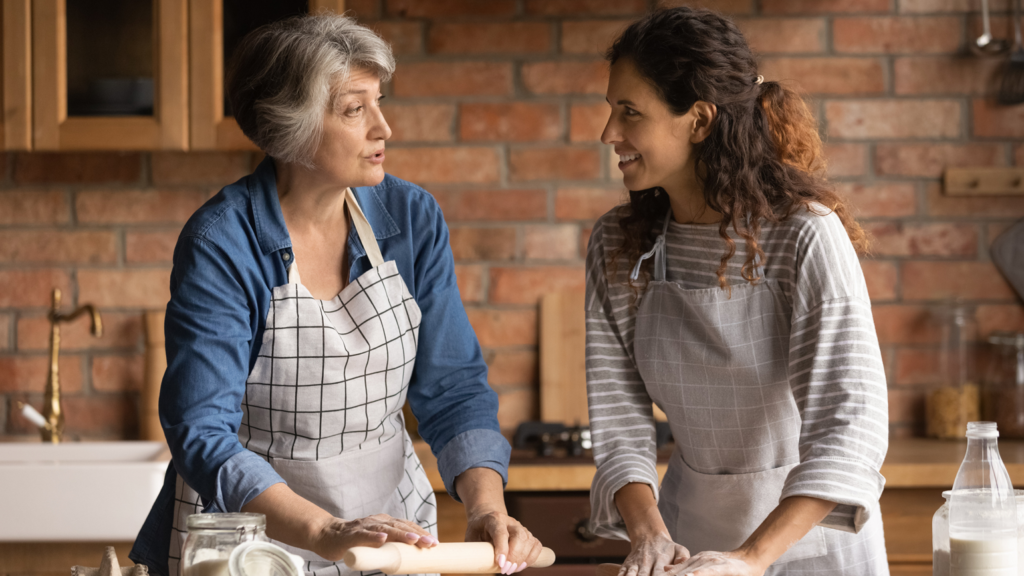 Young woman preparing food in kitchen with aging mother; Getty Images