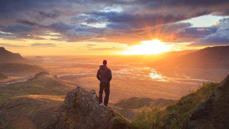 A man stands atop a mountain